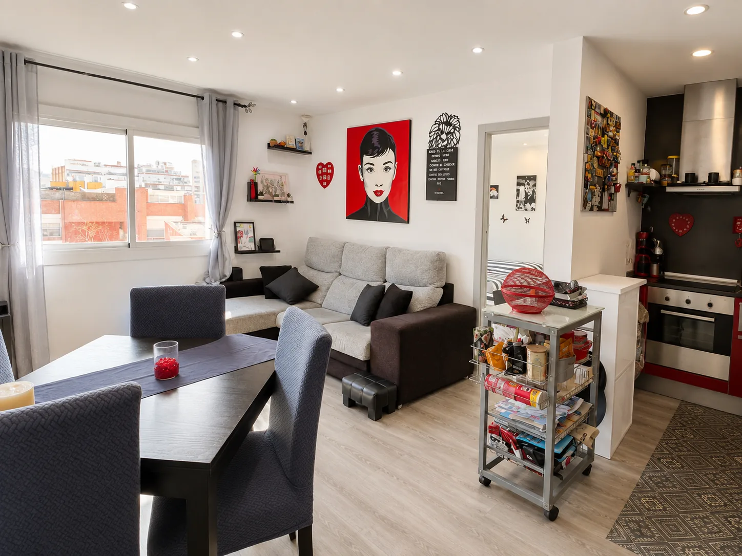 Salón luminoso con ventana al frente y cocina abierta
